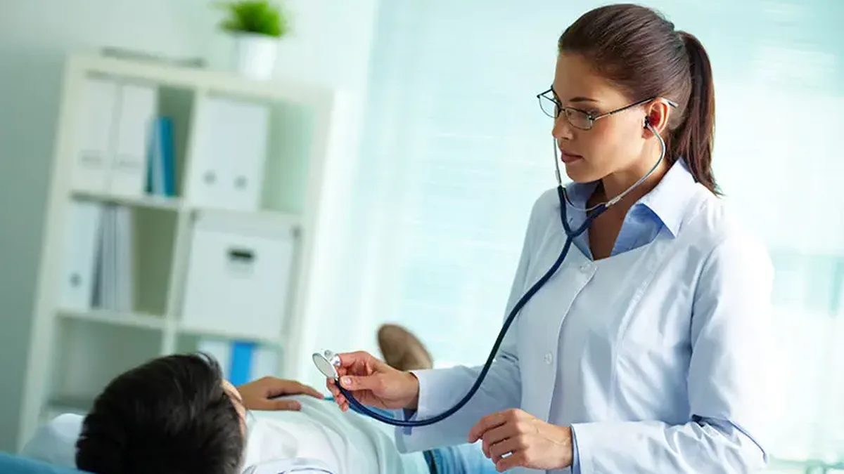 Une jeune médecin généraliste consulte un patient au cabinet