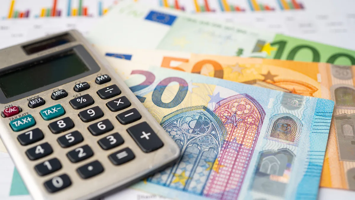 Des billets en euros et une calculatrice posés sur un bureau
