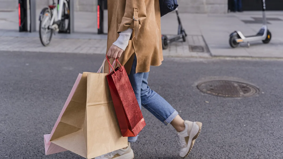 Une femme traverse la rue avec plusieurs sacs de courses