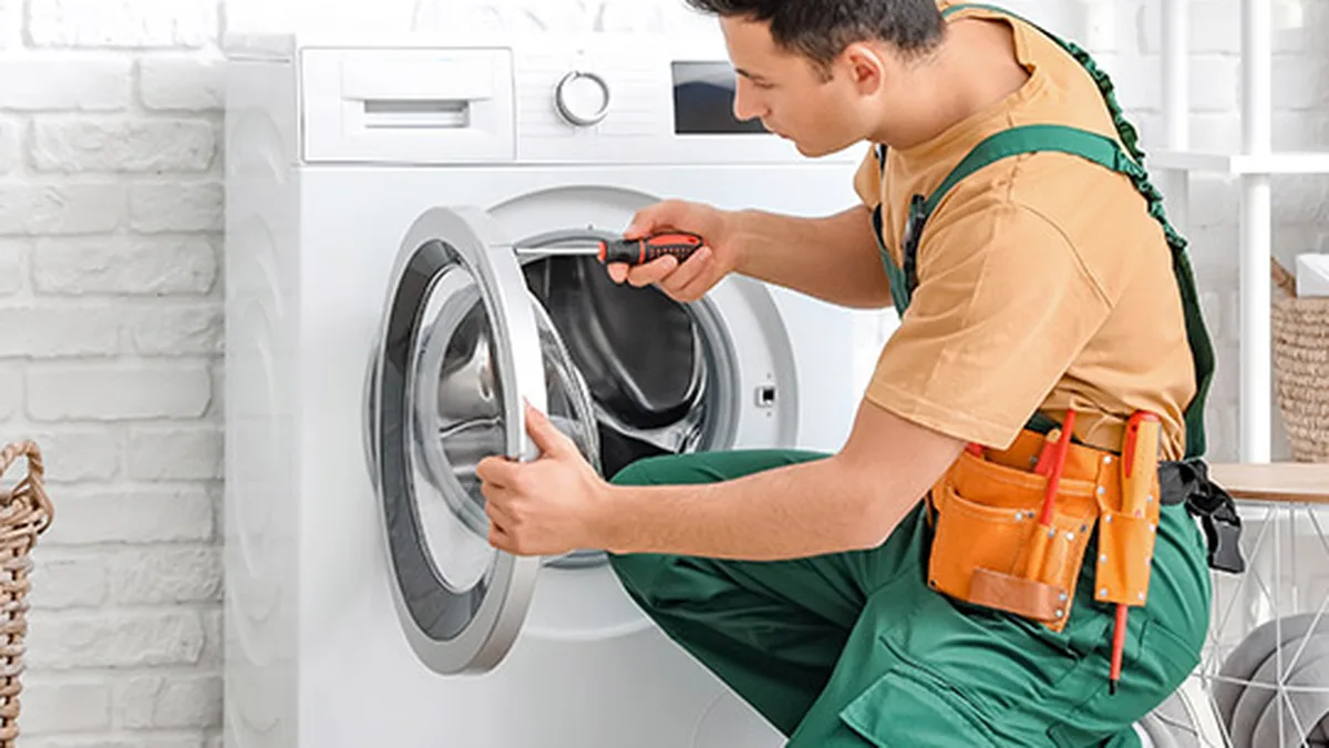 Un technicien dépanne un lave-linge à domicile
