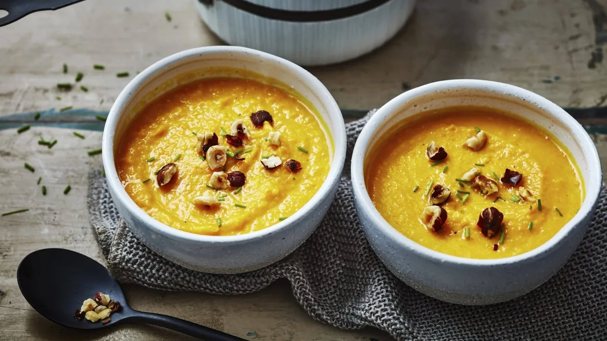Deux bols de velouté de patate douce parsemés de noisettes concassées