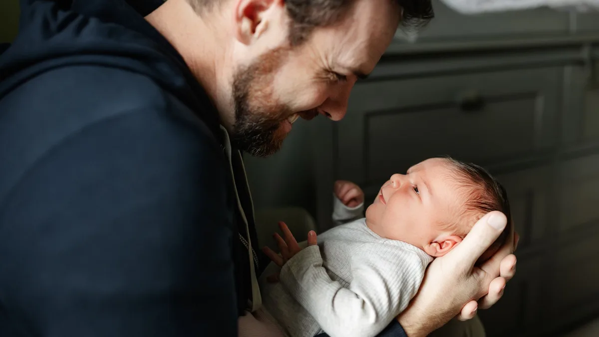 Un père regarde son nouveau-né, tenu dans ses bras à la maison