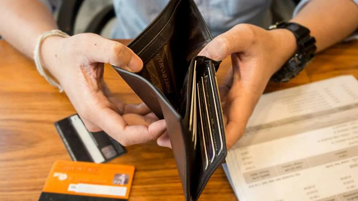 Un portefeuille vide ouvert au-dessus de relevés bancaires