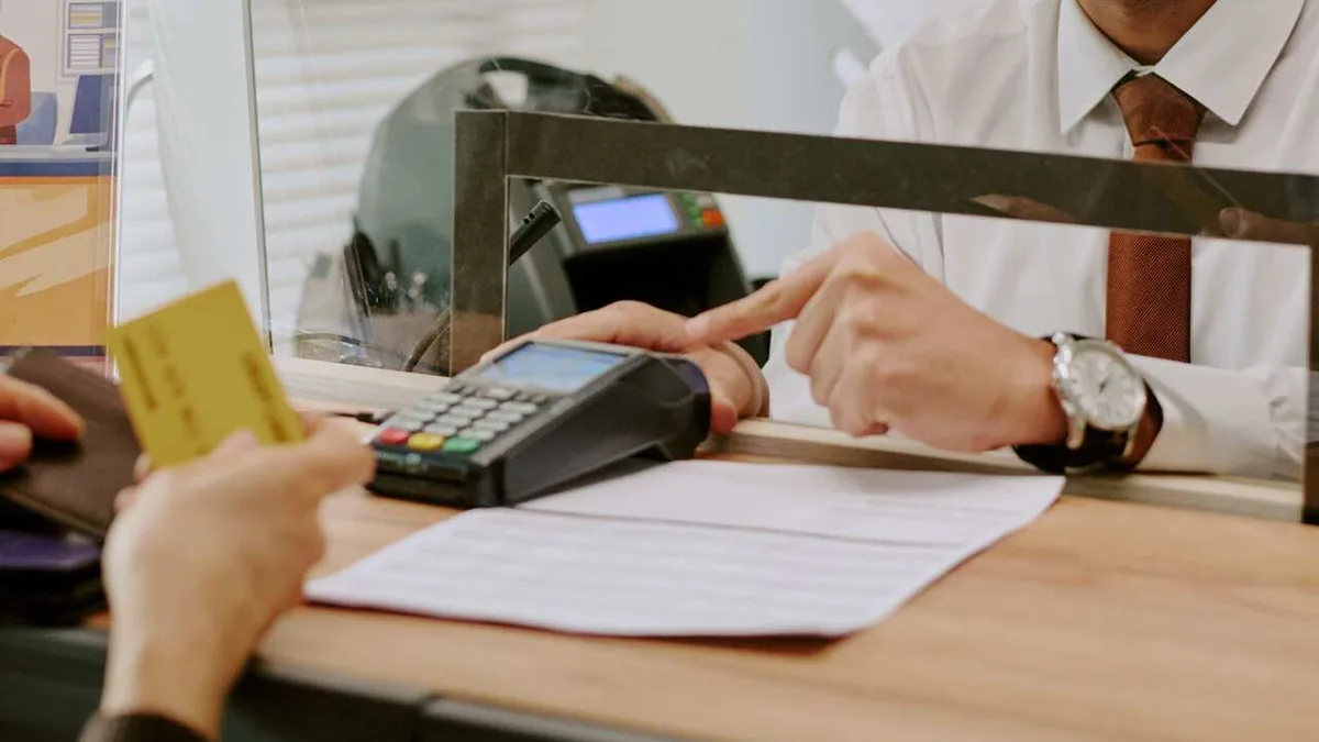 Un client paie par carte au guichet d&rsquo;une agence bancaire