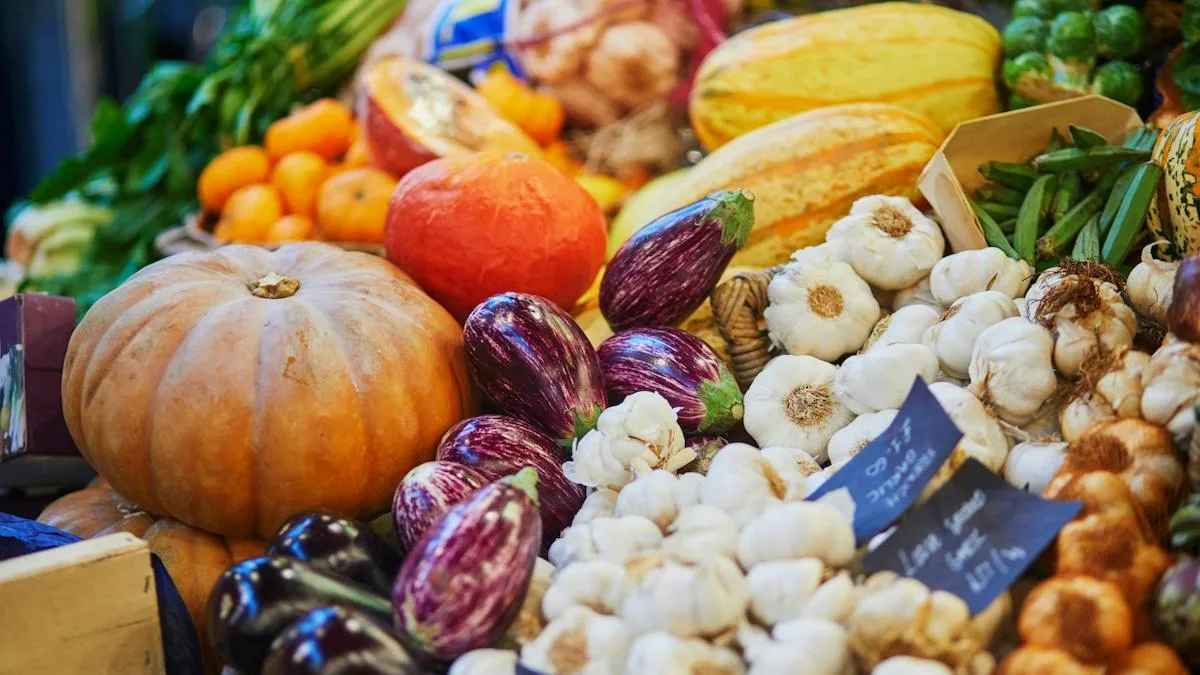 Un étal de marché en automne, avec courges, ail et légumes de saison