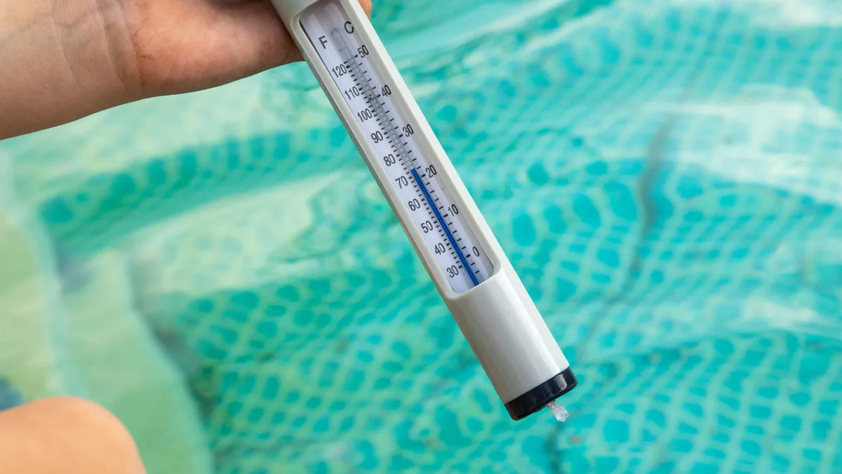 Une main tient un thermomètre de piscine