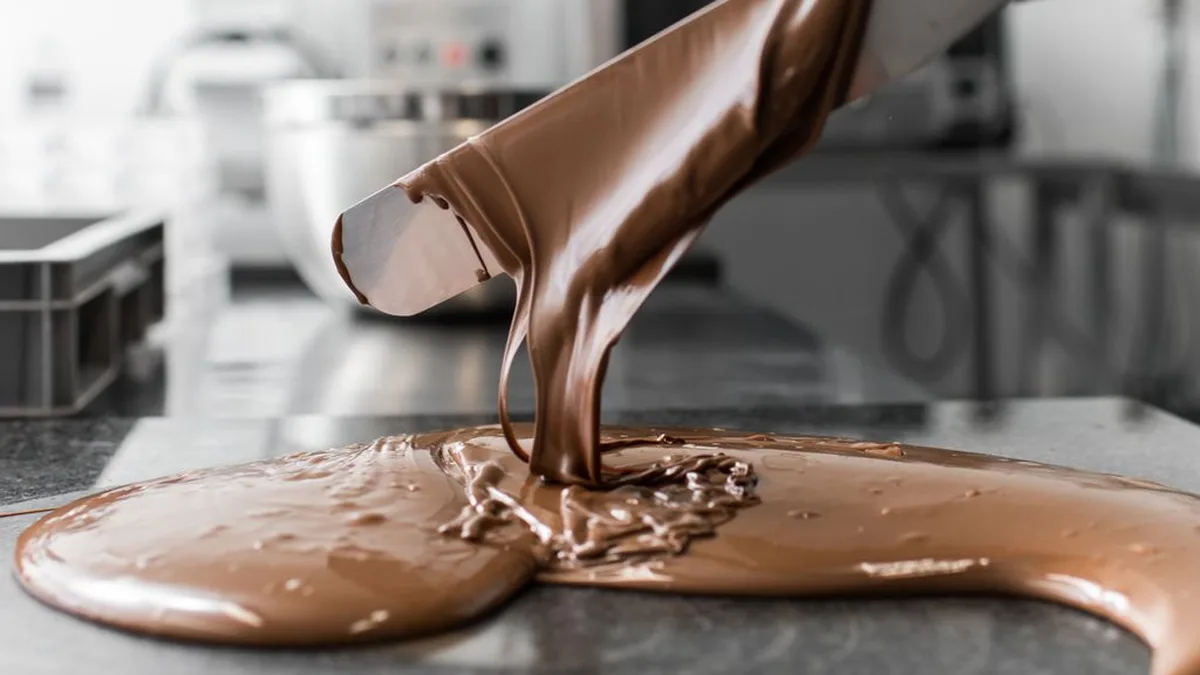 Un chocolatier en train de tempérer du chocolat fondu au marbre