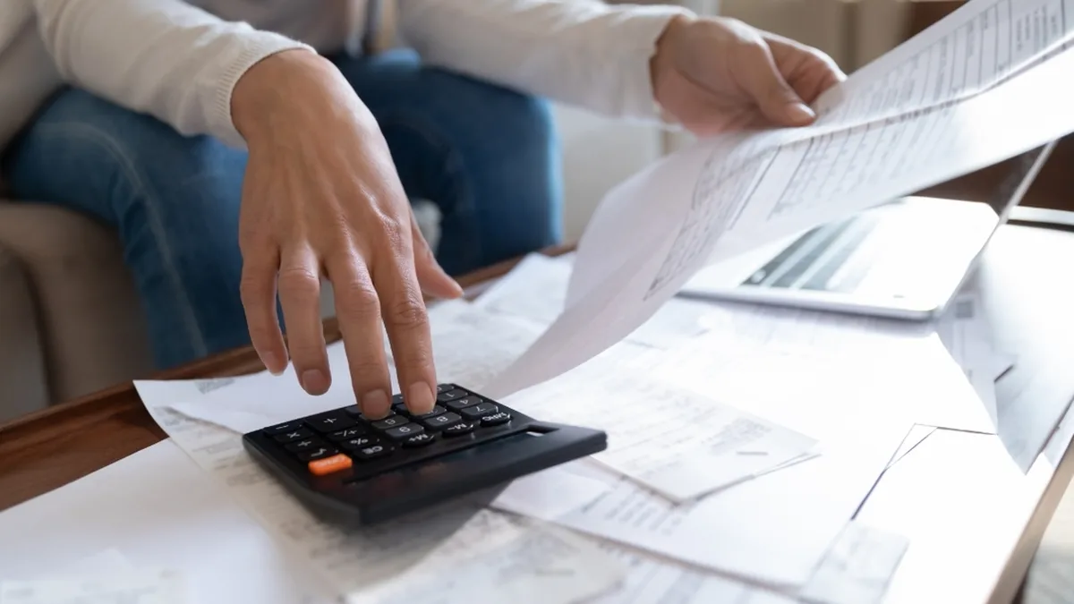 Une personne vérifie ses factures et ses calculs à la table de son salon