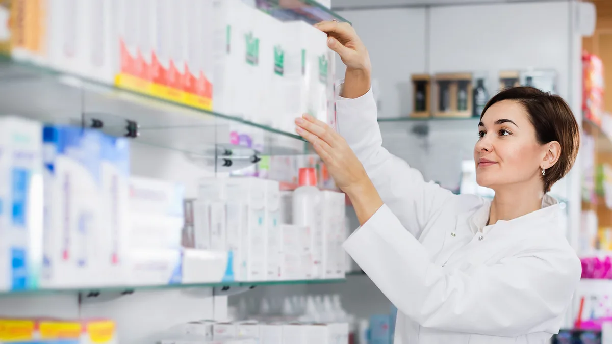 Une pharmacienne range des boîtes de médicaments sur les rayons d&rsquo;une officine