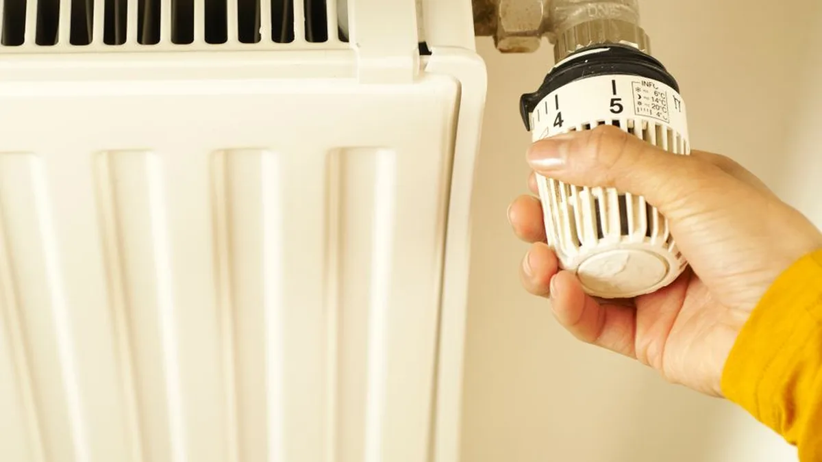 Une main règle le thermostat d&rsquo;un radiateur