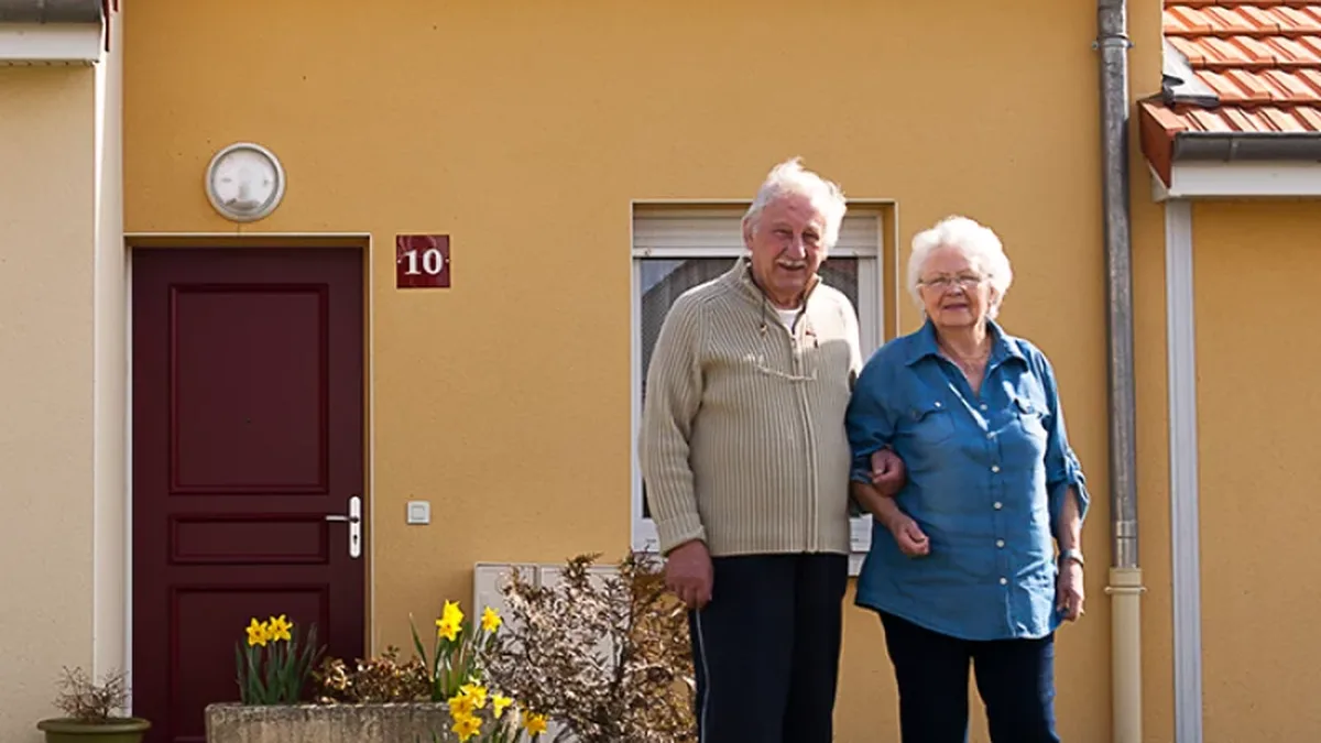 Un couple de retraités devant sa maison