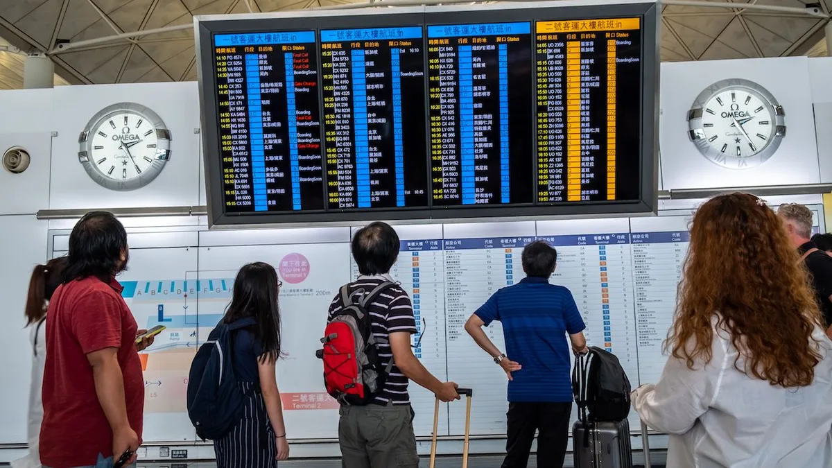 Des voyageurs consultent un tableau des départs dans un aéroport