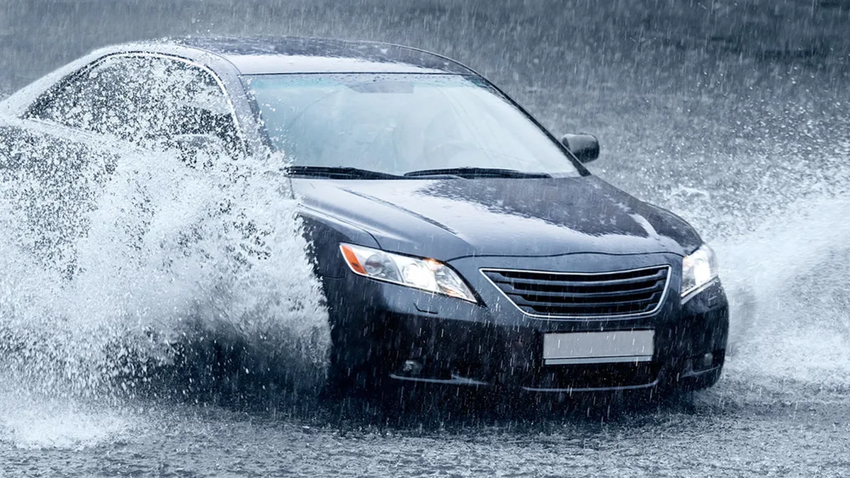 Une voiture traversant une chaussée détrempée sous une pluie battante