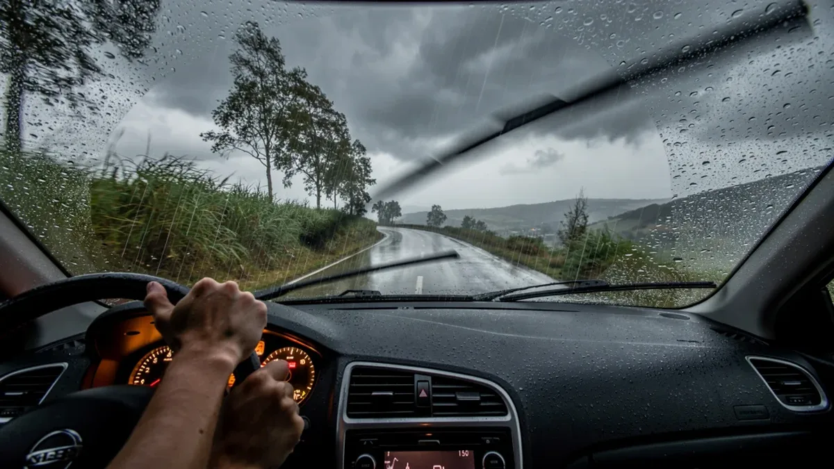 Un automobiliste conduit sous une pluie battante, essuie-glaces en marche