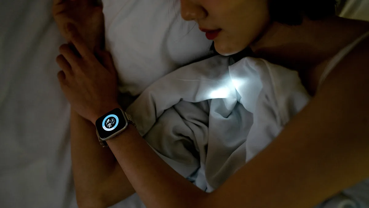 Une femme éveillée dans son lit regarde sa montre connectée