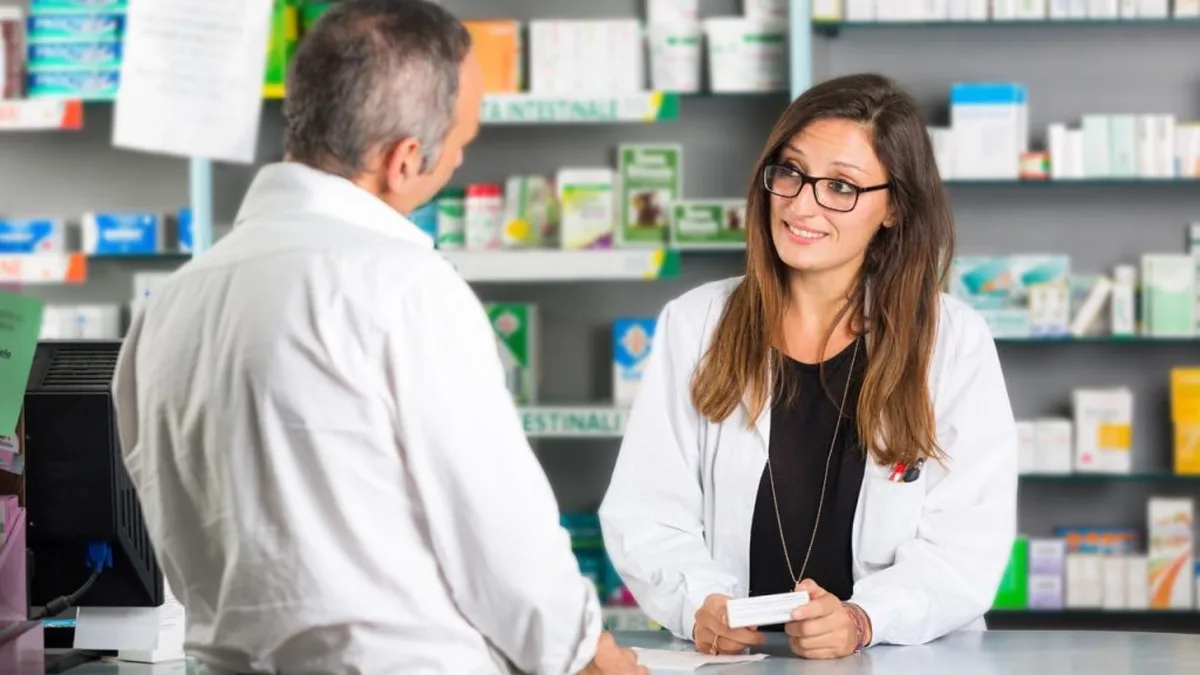 Une pharmacienne conseille un client au comptoir d&rsquo;une officine