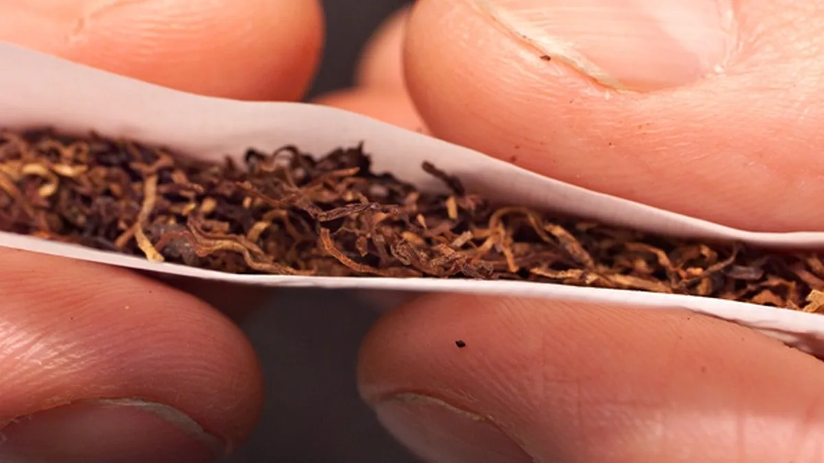 Une main roule une cigarette avec du tabac à rouler