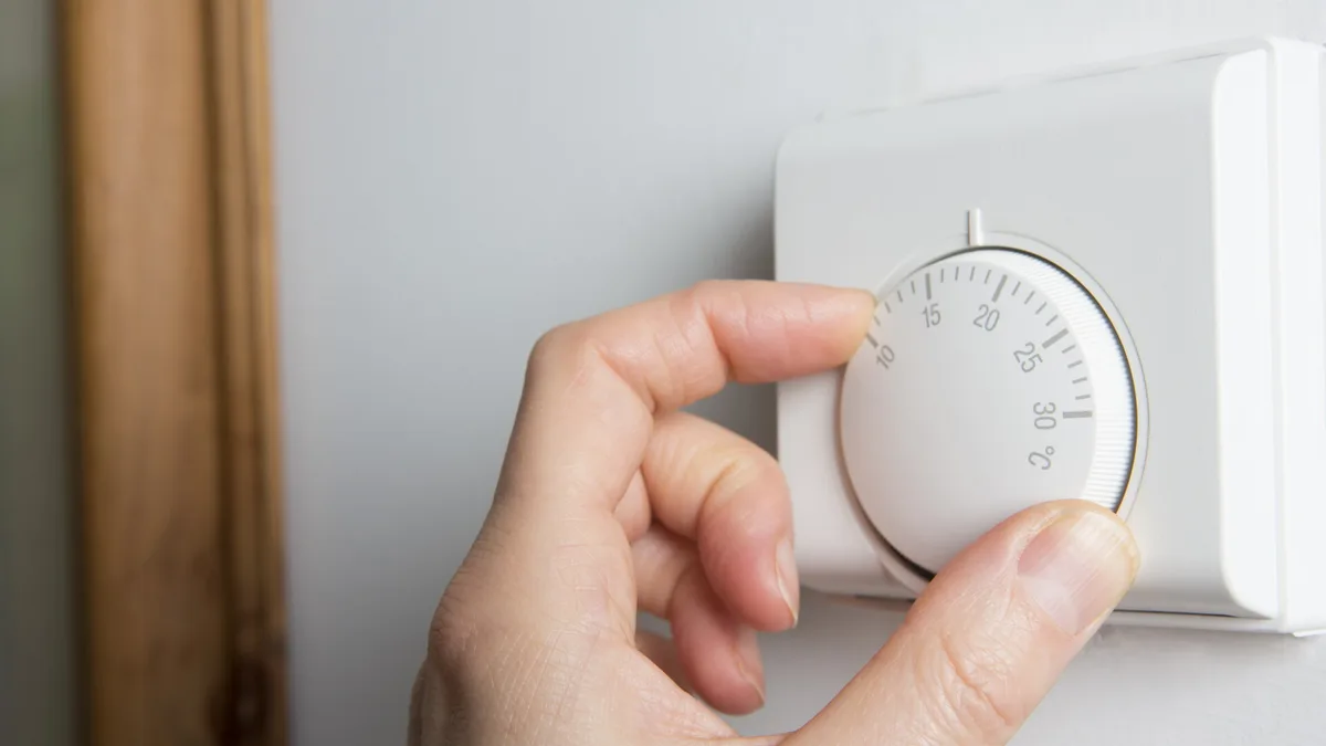Main réglant un thermostat d&rsquo;ambiance