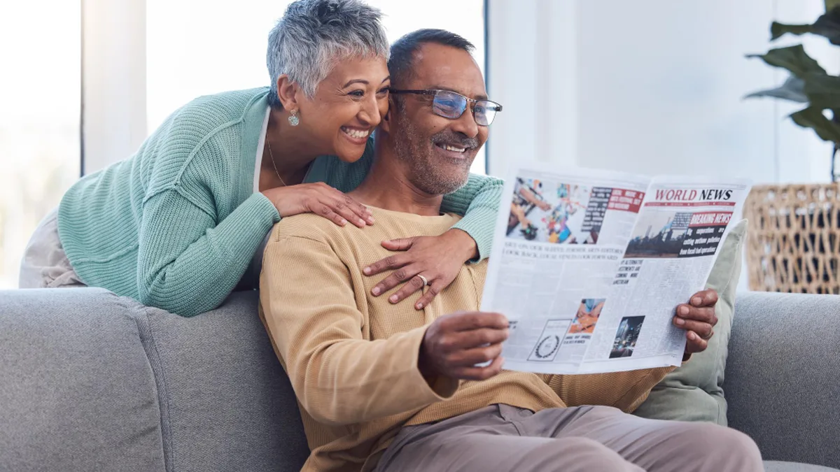 Un couple de retraités lit le journal à la maison