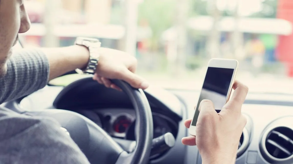 Un conducteur tient son smartphone en main au volant
